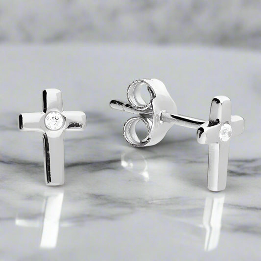 Silver cross-shaped earrings with clear gemstones on a white background