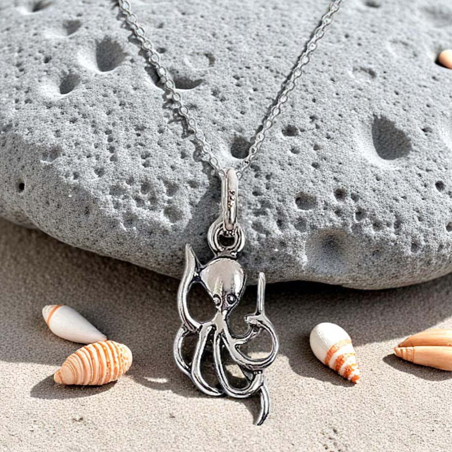 Silver octopus pendant necklace on a stone with shells
