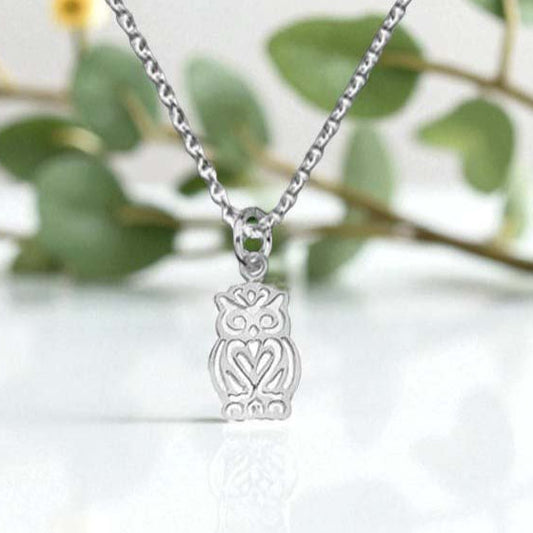 Silver owl pendant necklace on a blurred green leaf background